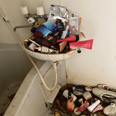 洗面器がゴミで溢れ、異臭を放つ大阪市西区ゴミ屋敷ワンルームのバスルーム片付け作業
